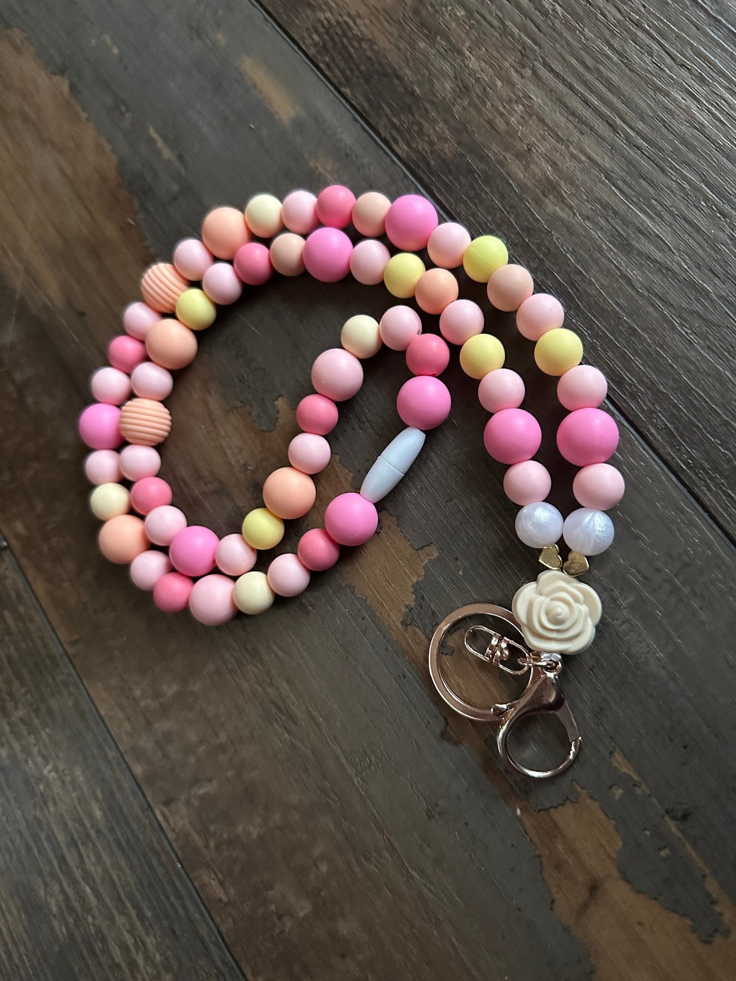 Sunset pattern silicone bead lanyard perfect for teachers and nurses. Great gift for teacher appreciation day! This lanyard is made with a gold lobster clasp and a breakaway Closure. There’s a large rose pendant bead by the clasp.